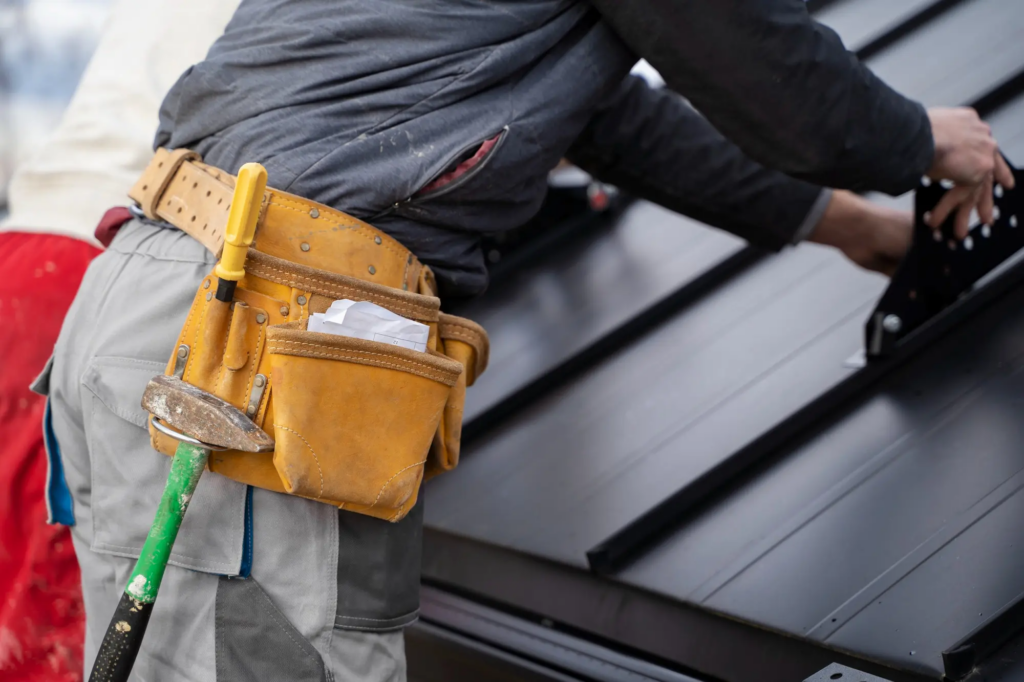 Artisan portant une ceinture à outils, au travail sur une toiture métallique