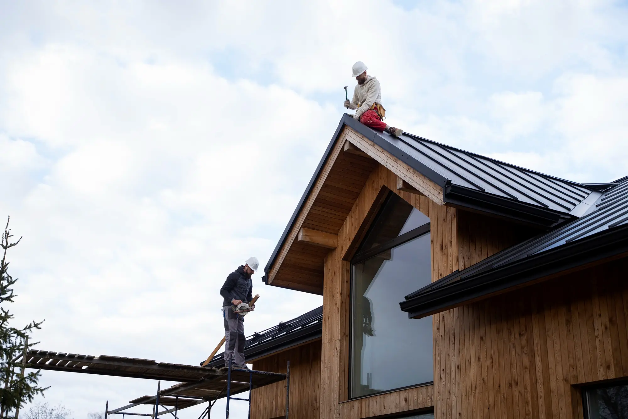 Deux couvreurs au travail sur la toiture d'une maison à ossature bois